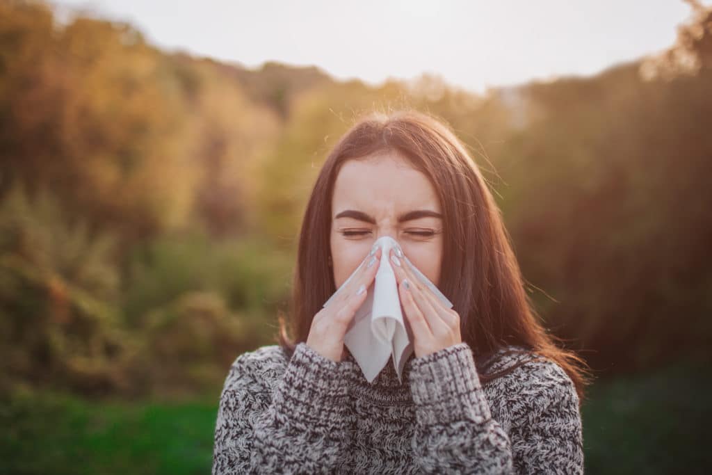 Woman blowing nose with tissue to relieve sinus congestion